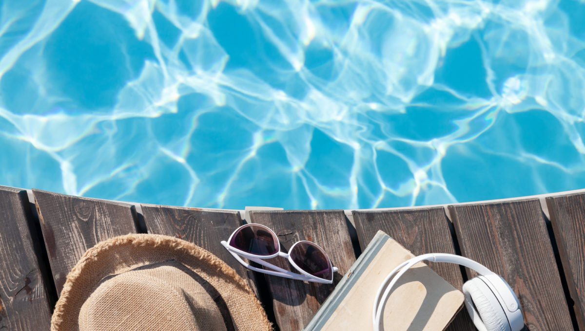 Book and headphones near swimming pool
